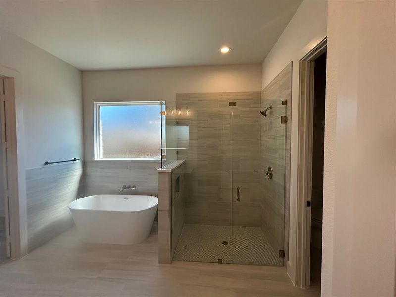 Primary bathroom with freestanding tub and separate shower with frameless glass door