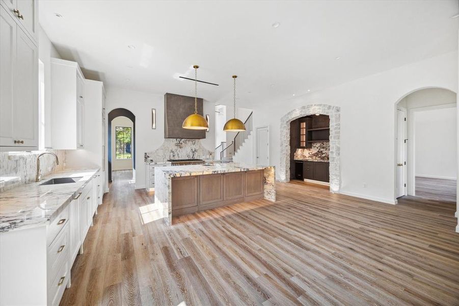 A full view of the kitchen area with custom inset cabinetry, 2 sinks, 2 Thermador panel ready dishwashers, 48" Thermador range, custom brass hardware and plaster vent hood liner, and marble countertops and backsplash.