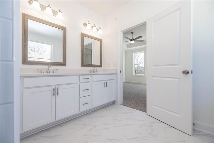 The primary bath has a double vanity with undermount sinks, venetian marble countertops and framed mirrors.