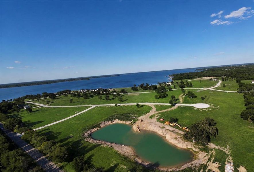 Expansive waterfront property featuring a large body of water, green landscape, and established roadways Expansive waterfront property featuring a large body of water, green landscape, and established roadways