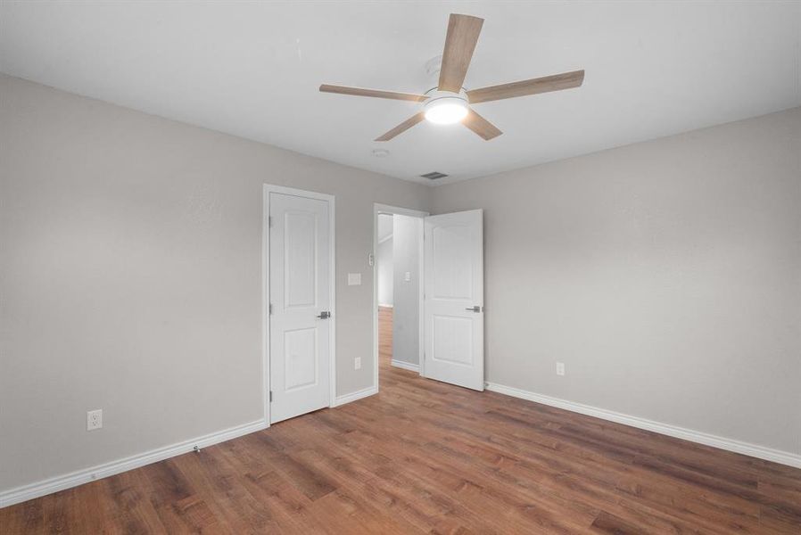 Unfurnished bedroom with ceiling fan and dark wood-type flooring Unfurnished bedroom with ceiling fan and dark wood-type flooring