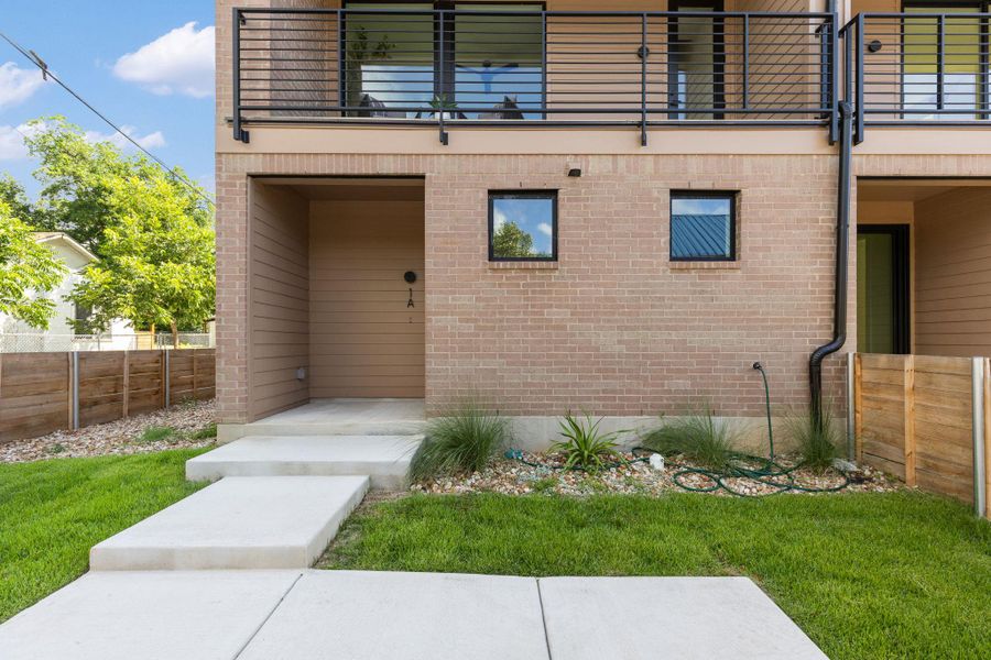 A modern facade with brick and horizontal siding, offering a second-story balcony and ground-level entry. A modern facade with brick and horizontal siding, offering a second-story balcony and ground-level entry.