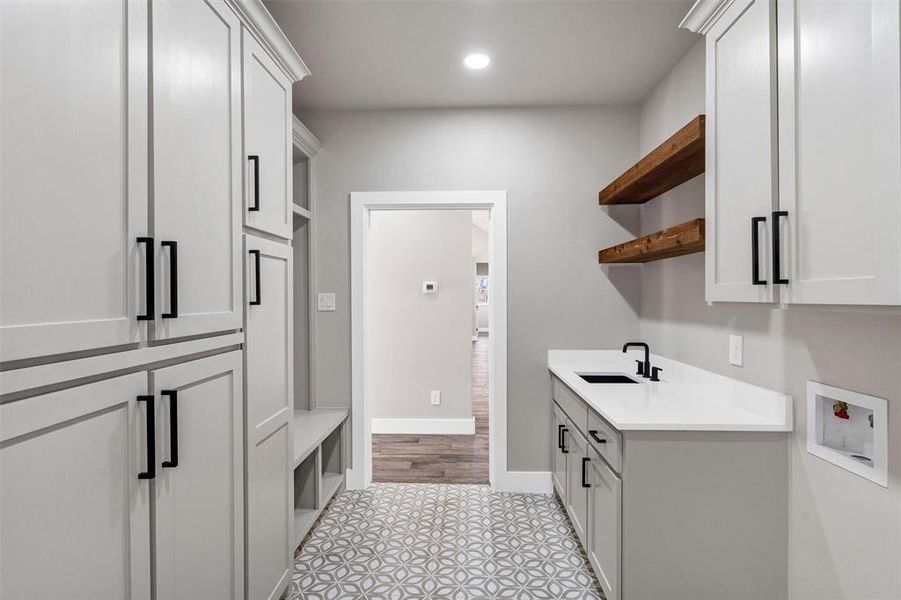 Washroom with hookup for a washing machine, sink, and cabinets