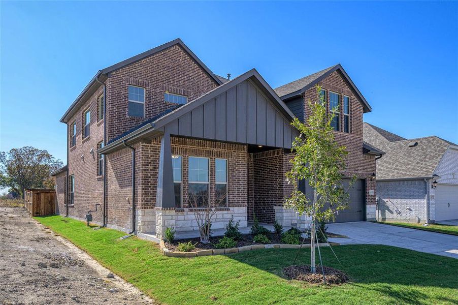 View of front of house with brick siding, a front yard, board and batten siding, and concrete driveway