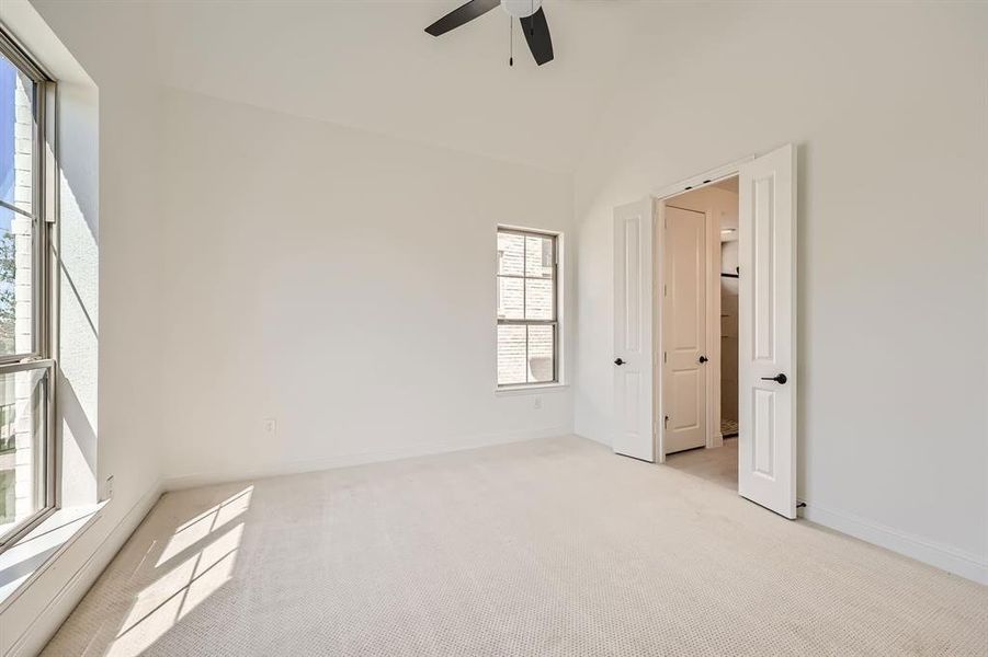 Unfurnished room featuring ceiling fan, light colored carpet, and vaulted ceiling