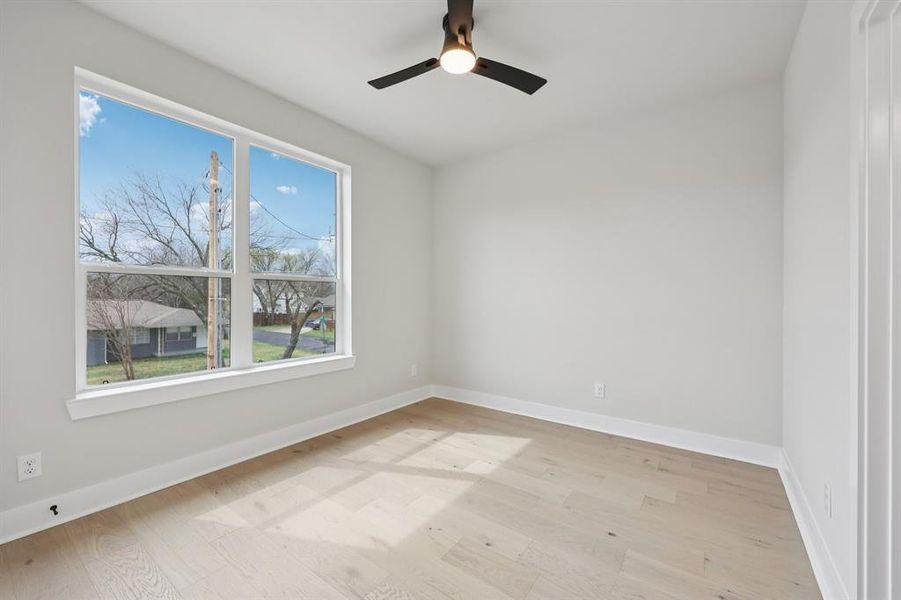 Spacious room featuring wood-finish flooring, white baseboards, and a large window with white trim