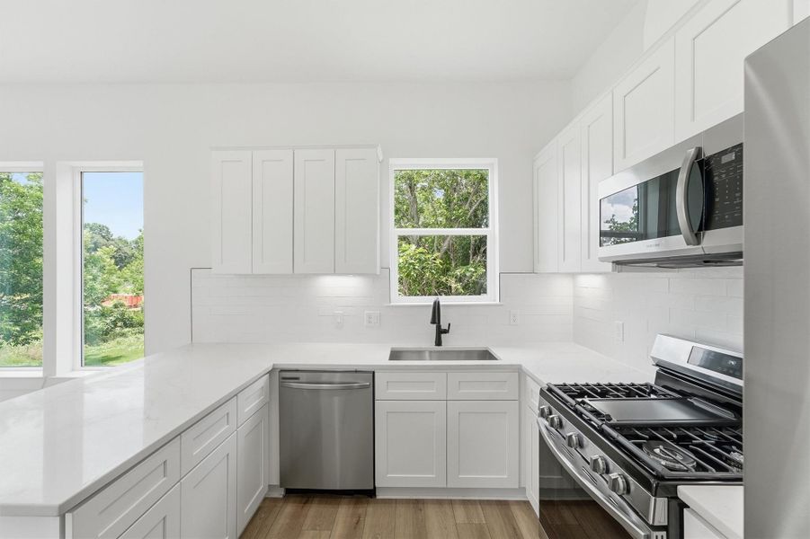 There's something magical about washing dishes with a view. This bright kitchen sink wall features a matte black faucet, stainless undermount sink, quartz countertops, and dual windows overlooking lush greenery that make everyday moments feel special. There's something magical about washing dishes with a view. This bright kitchen sink wall features a matte black faucet, stainless undermount sink, quartz countertops, and dual windows overlooking lush greenery that make everyday moments feel special.