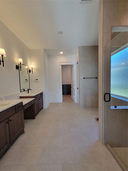 This spacious bathroom features dual sinks with elegant dark wood cabinets, a large walk-in shower with a glass door, and stylish wall sconces for lighting. Neutral tile flooring enhances the clean and modern look. This spacious bathroom features dual sinks with elegant dark wood cabinets, a large walk-in shower with a glass door, and stylish wall sconces for lighting. Neutral tile flooring enhances the clean and modern look.