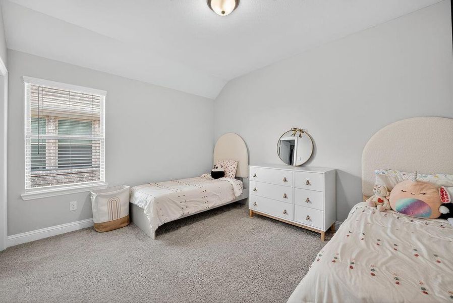 Spacious room featuring light gray walls, plush gray carpeting, and a window with horizontal blinds
