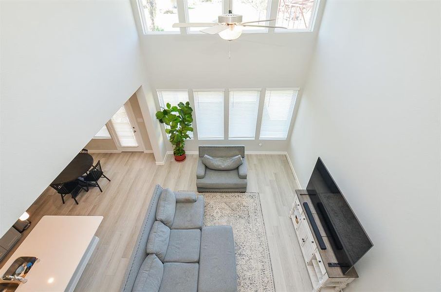 This bright, airy living space features a high ceiling with large windows that let in natural light.  The neutral tones and modern design create a welcoming atmosphere.