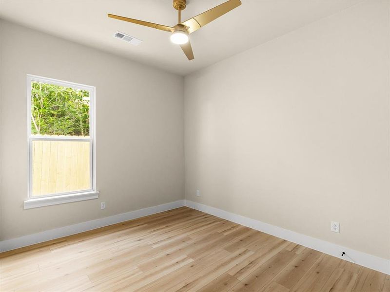 Room with wood-finish flooring, light-colored walls, and a contemporary ceiling fan with integrated lighting