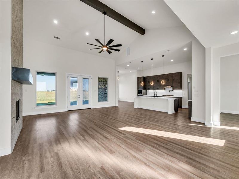 Unfurnished living room featuring beamed ceiling, dark wood-type flooring, a fireplace, high vaulted ceiling, and ceiling fan