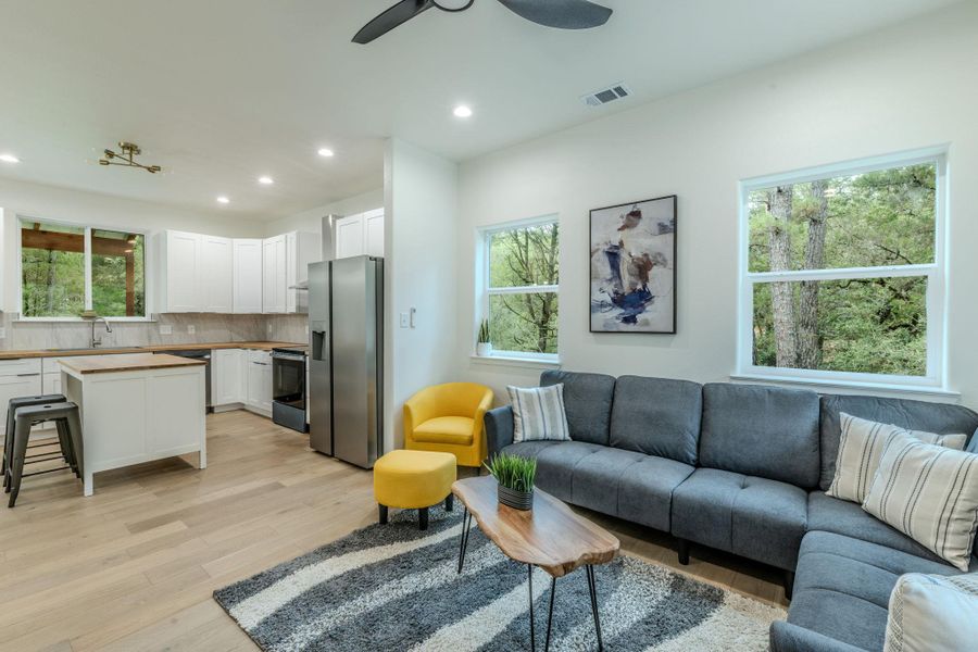 An open-concept living space integrates a well-appointed kitchen with a comfortable lounge area, all bathed in natural light from large windows overlooking greenery. An open-concept living space integrates a well-appointed kitchen with a comfortable lounge area, all bathed in natural light from large windows overlooking greenery.