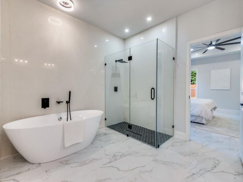 Ensuite bathroom featuring marble finish flooring, a stall shower, a freestanding bath, and recessed lighting.