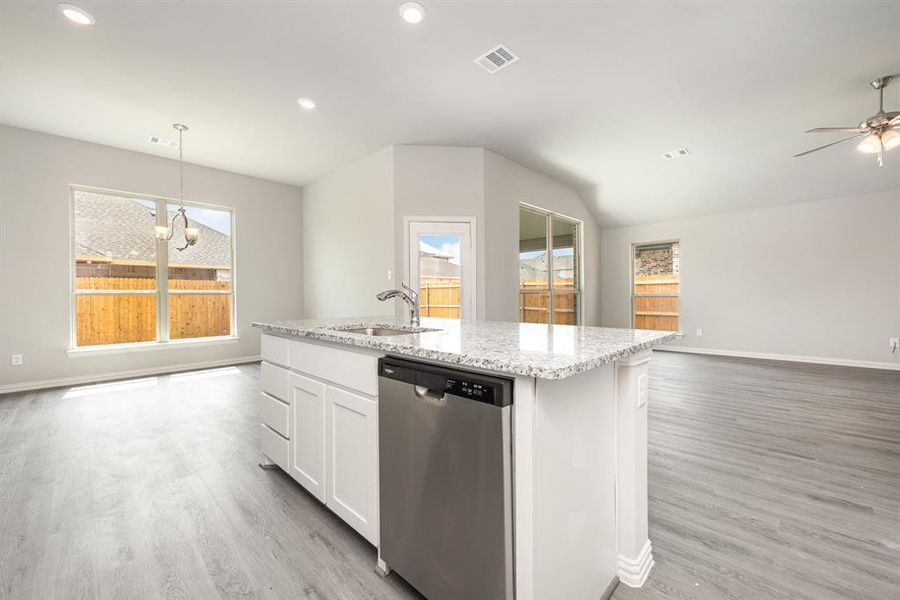 Kitchen with stainless steel dishwasher, white cabinetry, plenty of natural light, and light hardwood / wood-style flooring