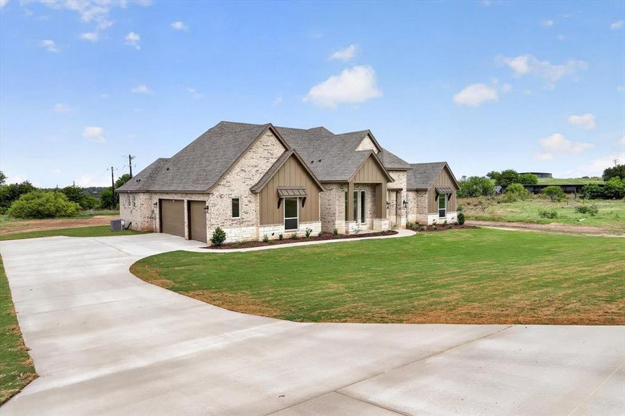 Single-story residence featuring a brick and stone facade, a multi-gabled roofline, and a two-car attached garage Single-story residence featuring a brick and stone facade, a multi-gabled roofline, and a two-car attached garage