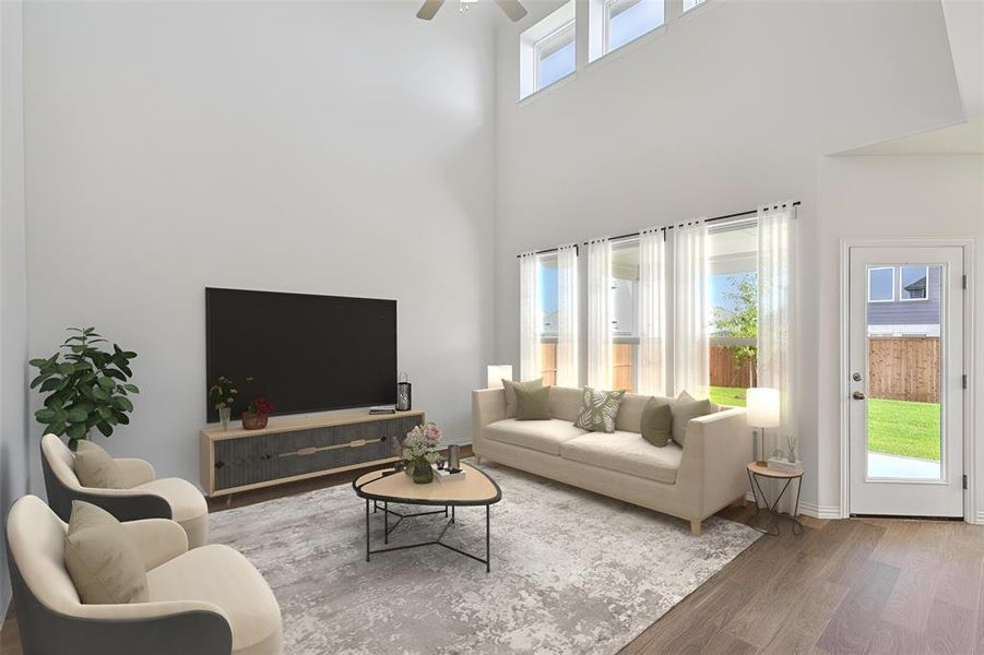 Living room featuring ceiling fan, a towering ceiling, and hardwood / wood-style floors