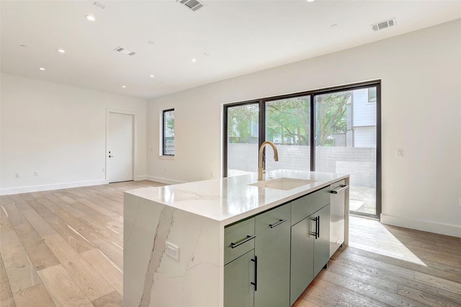 Kitchen featuring light wood-style floors, recessed lighting, an island with sink, light stone counters, and open floor plan