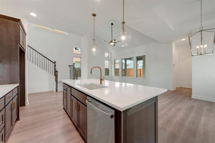 Kitchen island featuring a white countertop, undermount sink, and brass-finish faucet