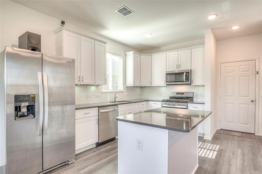 Kitchen featuring appliances with stainless steel finishes, white cabinets, backsplash, and recessed lighting Kitchen featuring appliances with stainless steel finishes, white cabinets, backsplash, and recessed lighting