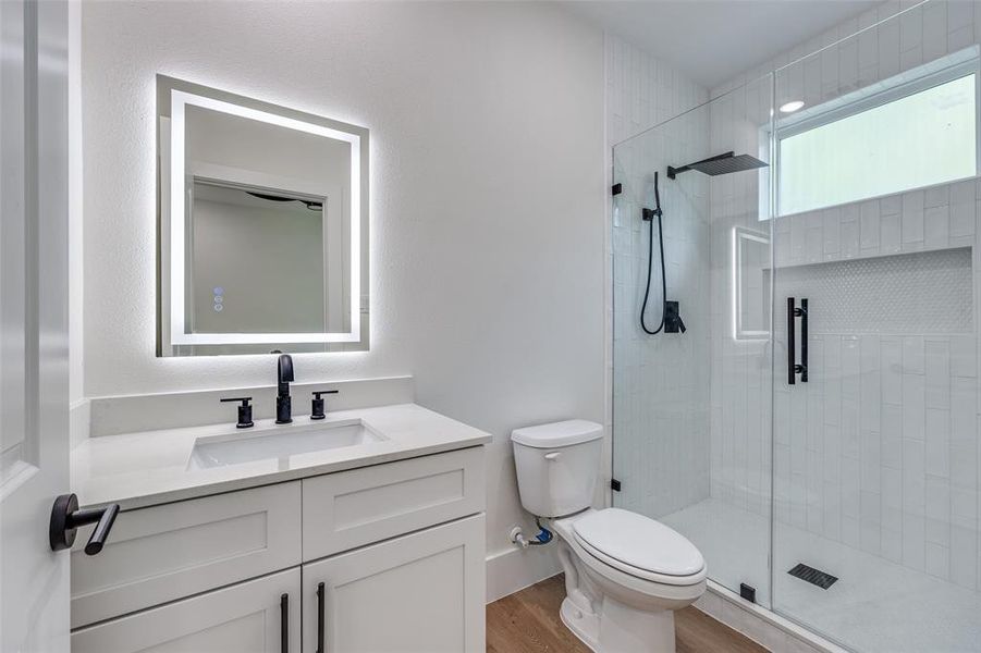 Bathroom featuring a shower stall, vanity, and wood finished floors Bathroom featuring a shower stall, vanity, and wood finished floors