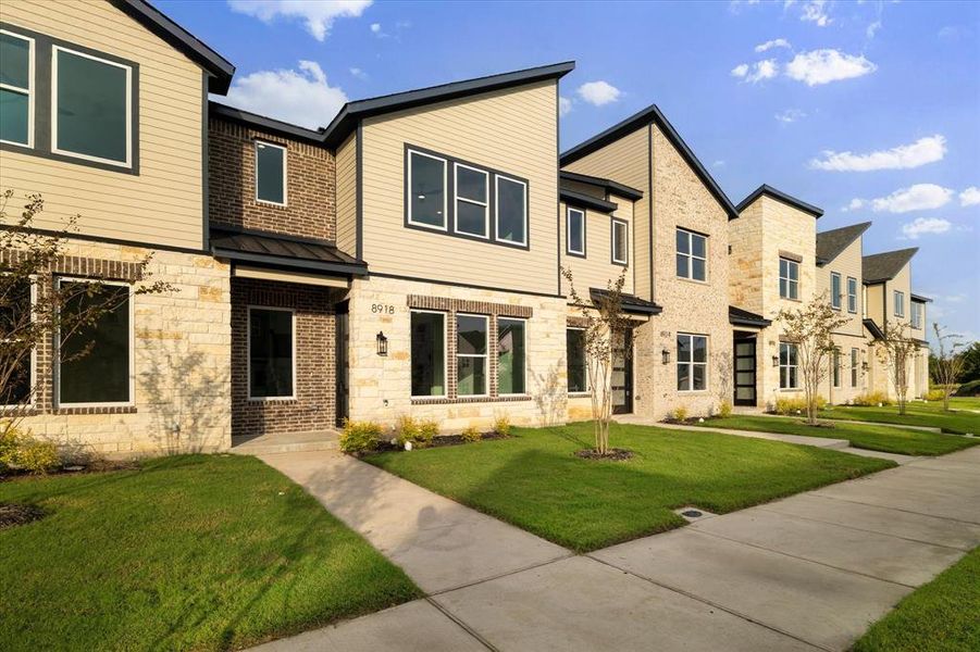 View of front of property with stone siding, a residential view, a front yard, a metal roof, and a standing seam roof View of front of property with stone siding, a residential view, a front yard, a metal roof, and a standing seam roof