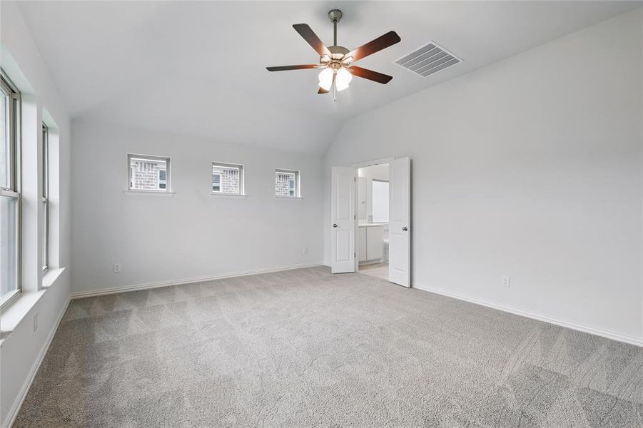 Unfurnished room with carpet flooring, a ceiling fan, visible vents, and lofted ceiling Unfurnished room with carpet flooring, a ceiling fan, visible vents, and lofted ceiling
