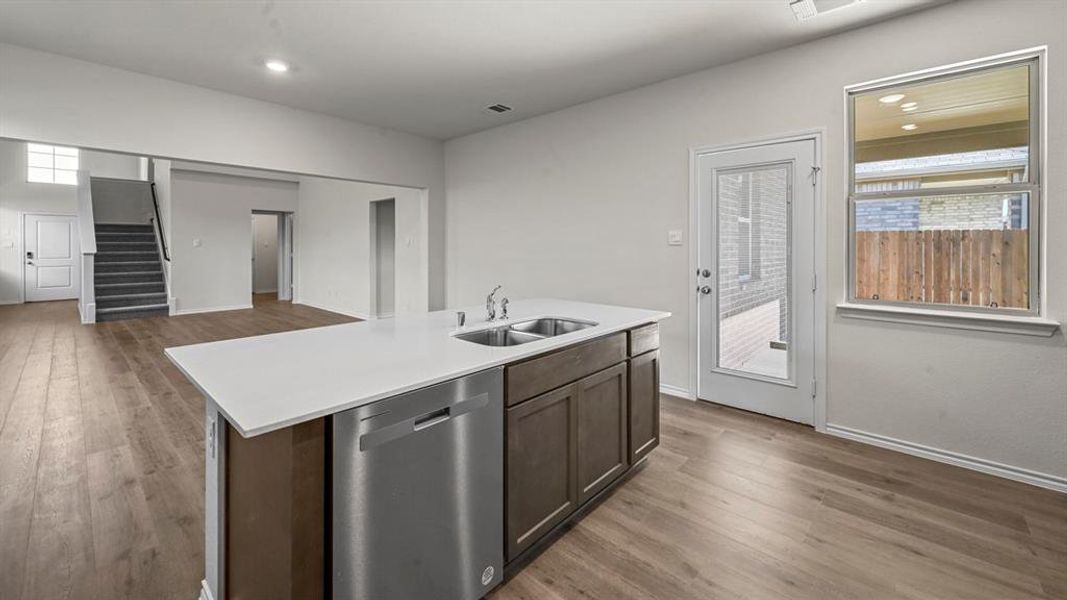 Kitchen island featuring a double-basin stainless steel sink, stainless steel dishwasher, and a light-toned countertop