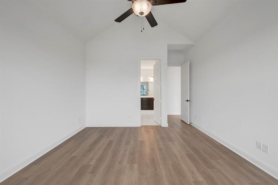 Empty room with lofted ceiling, dark wood-type flooring, and a ceiling fan