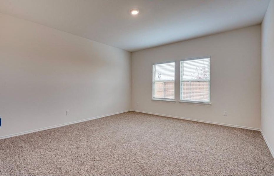 Spacious room featuring neutral carpet flooring, light-toned walls, and two windows with horizontal blinds Spacious room featuring neutral carpet flooring, light-toned walls, and two windows with horizontal blinds