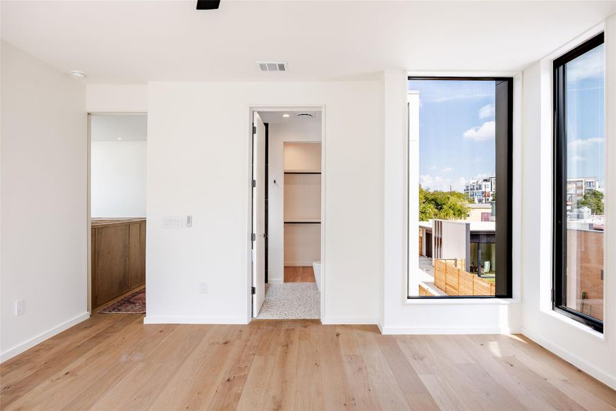 Unfurnished bedroom with light wood-type flooring, ensuite bath, and a ceiling fan