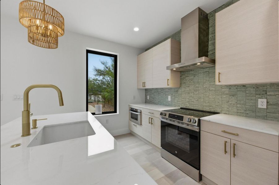 Kitchen with stainless steel appliances, modern cabinets, wall chimney exhaust hood, backsplash, and recessed lighting Kitchen with stainless steel appliances, modern cabinets, wall chimney exhaust hood, backsplash, and recessed lighting
