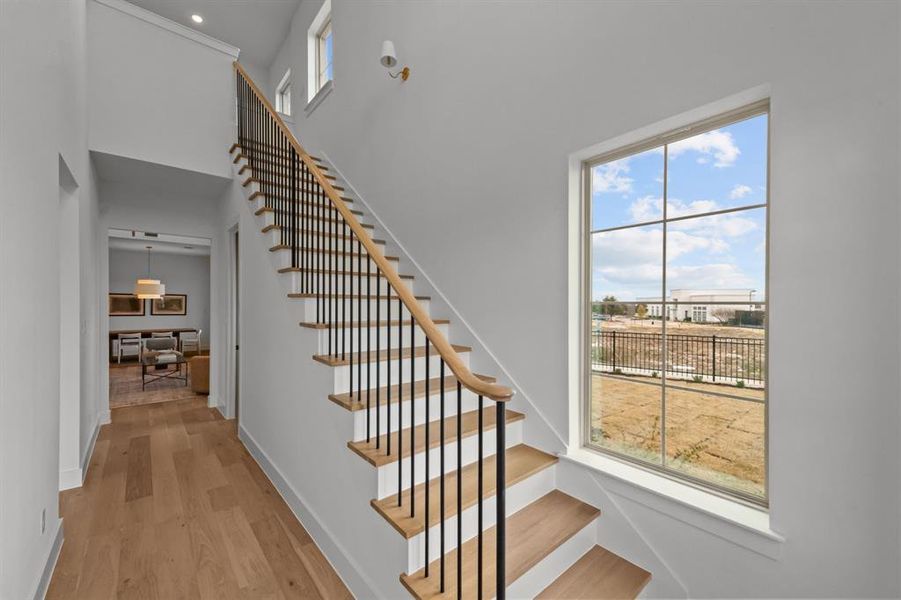 Stairs with hardwood floors and a high ceiling