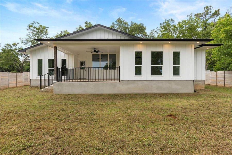 Rear view of property with a ceiling fan, a fenced backyard, and board and batten siding Rear view of property with a ceiling fan, a fenced backyard, and board and batten siding