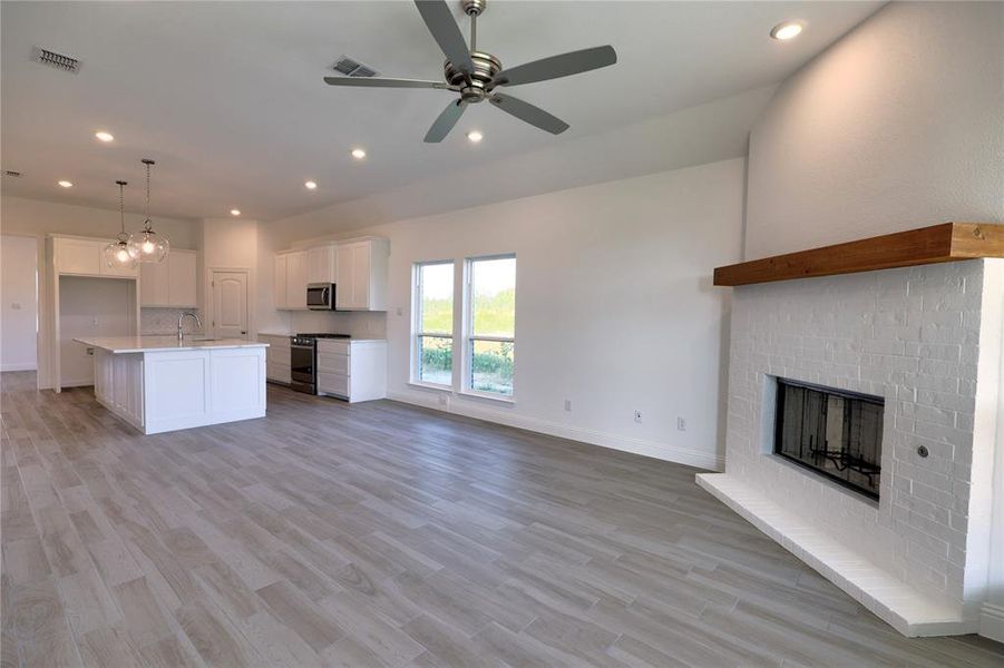 Kitchen featuring open floor plan, stainless steel appliances, white cabinets, recessed lighting, and light wood-type flooring Kitchen featuring open floor plan, stainless steel appliances, white cabinets, recessed lighting, and light wood-type flooring