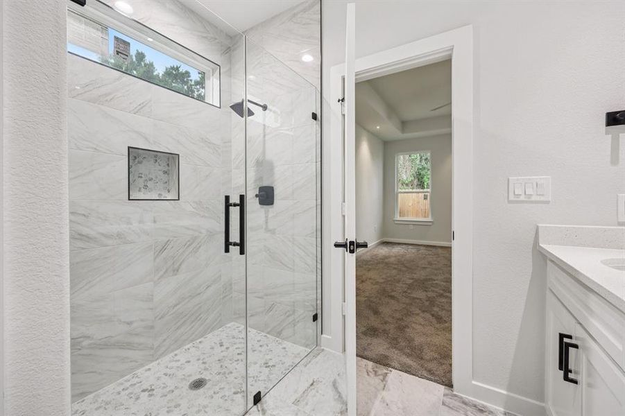 Full bathroom featuring a shower stall, vanity, and marble look tiles Full bathroom featuring a shower stall, vanity, and marble look tiles