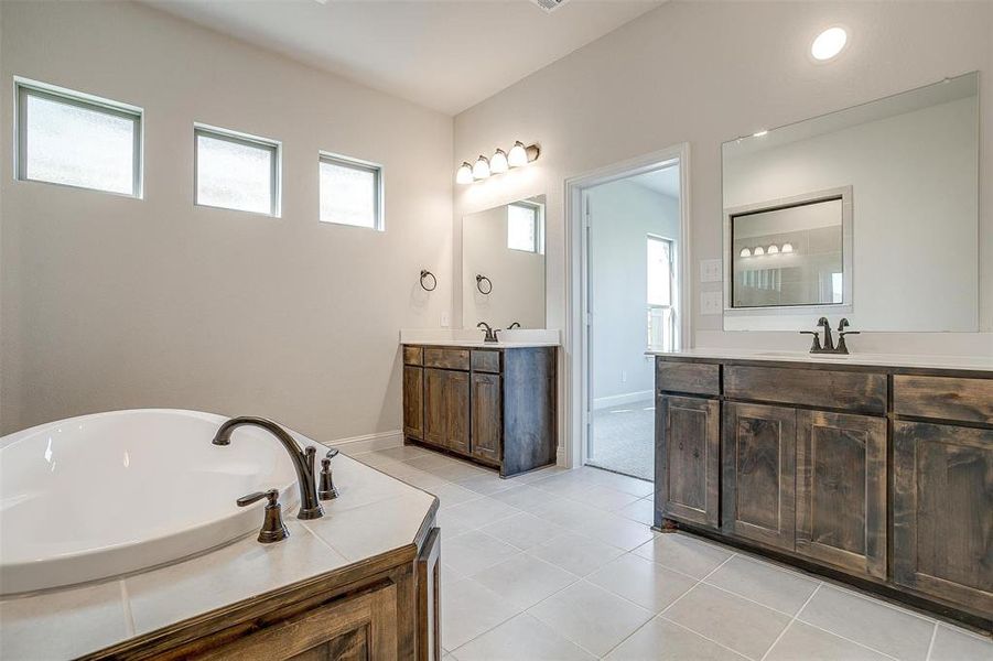 Bathroom with a bathtub, vanity, and tile patterned floors