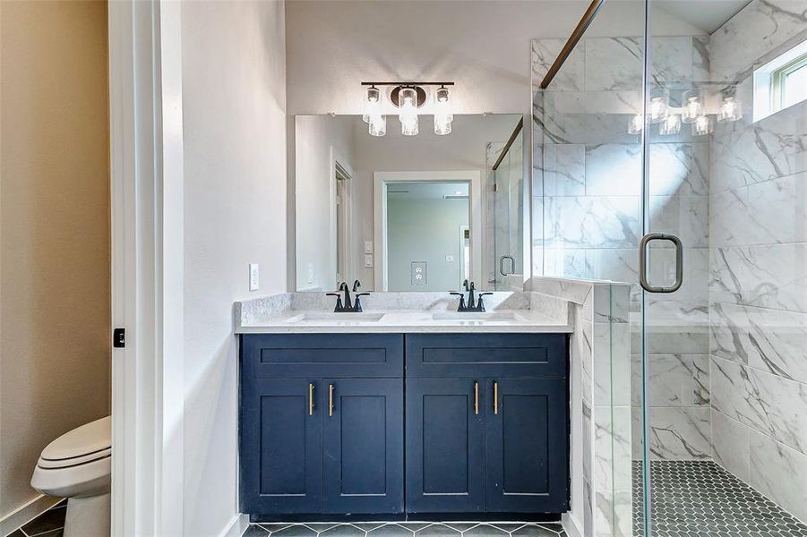 The ultimate in luxury, this bathroom boasts dual sinks, quartz counters, and a frameless glass shower with intricate tilework. It's a serene space designed for relaxation and functionality.