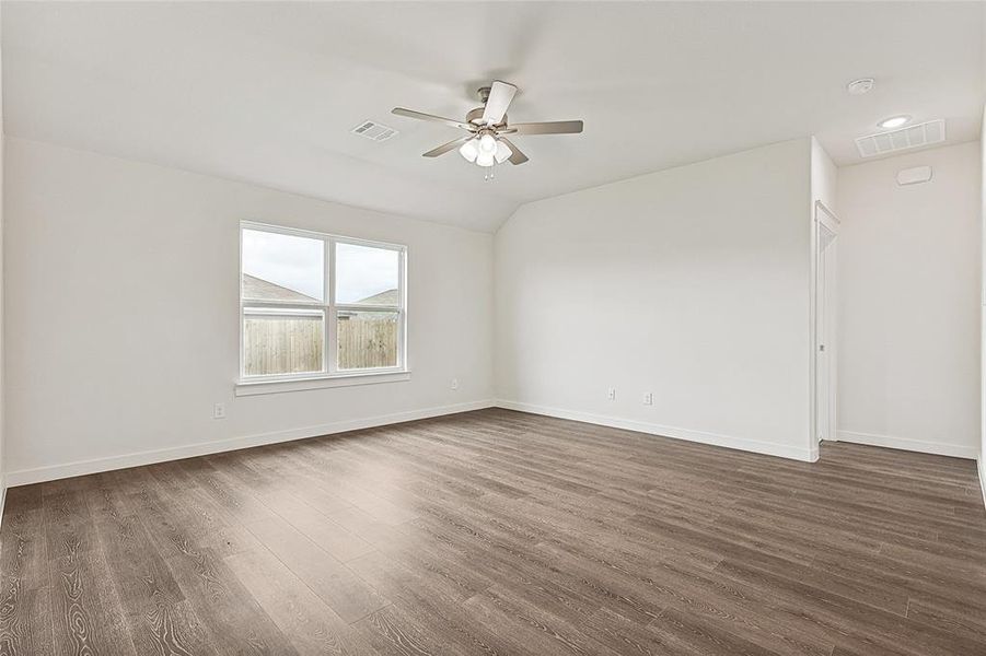 Spare room featuring dark wood-type flooring, vaulted ceiling, and ceiling fan