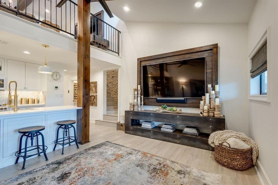 Living room featuring sink, high vaulted ceiling, and light hardwood / wood-style flooring