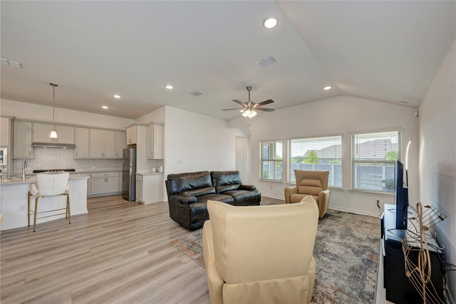An open concept design seamlessly connects the kitchen and living room, bathed in natural light from multiple windows.