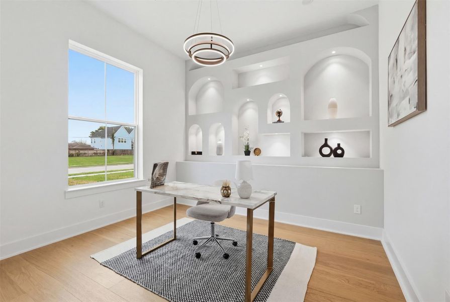 This distinctive office blends form and function with a statement chandelier, custom stucco wall with softly illuminated display niches. A large front-facing window invites abundant natural light, creating an inspiring workspace ideal for both productivity and presentation.