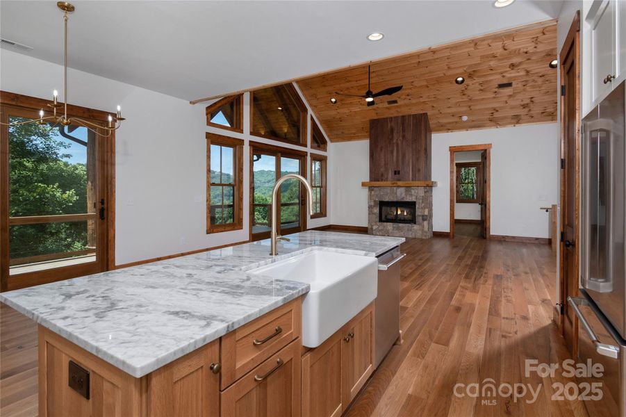 Chef's kitchen with custom solid wood cabinets, stainless steel appliances, farmhouse sink & dining room overlooking 2 story living room