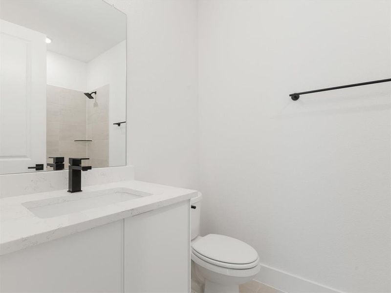 Ensuite bathroom featuring vanity, light tile patterned floors, and a tile shower