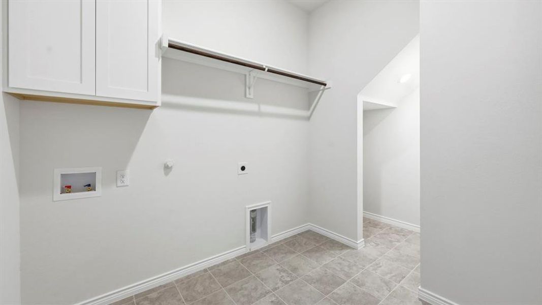 Laundry room featuring hookup for a gas dryer, washer hookup, hookup for an electric dryer, light tile patterned flooring, and cabinet space Laundry room featuring hookup for a gas dryer, washer hookup, hookup for an electric dryer, light tile patterned flooring, and cabinet space