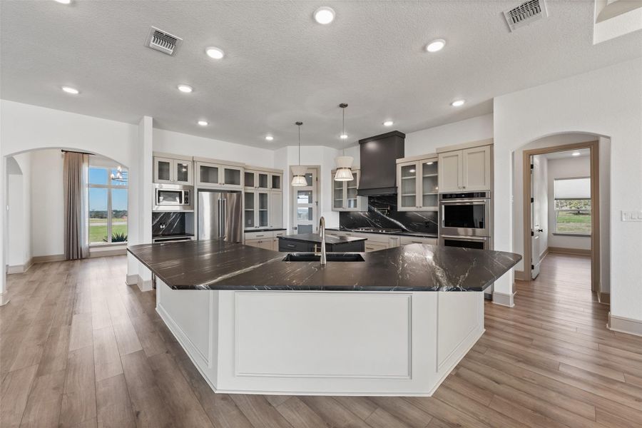 Kitchen featuring visible vents, arched walkways, appliances with stainless steel finishes, and a sink