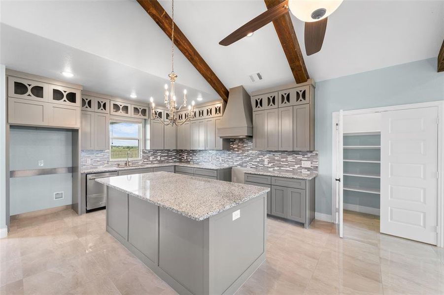 Kitchen with a kitchen island, stainless steel dishwasher, ceiling fan with notable chandelier, custom exhaust hood, and beam ceiling