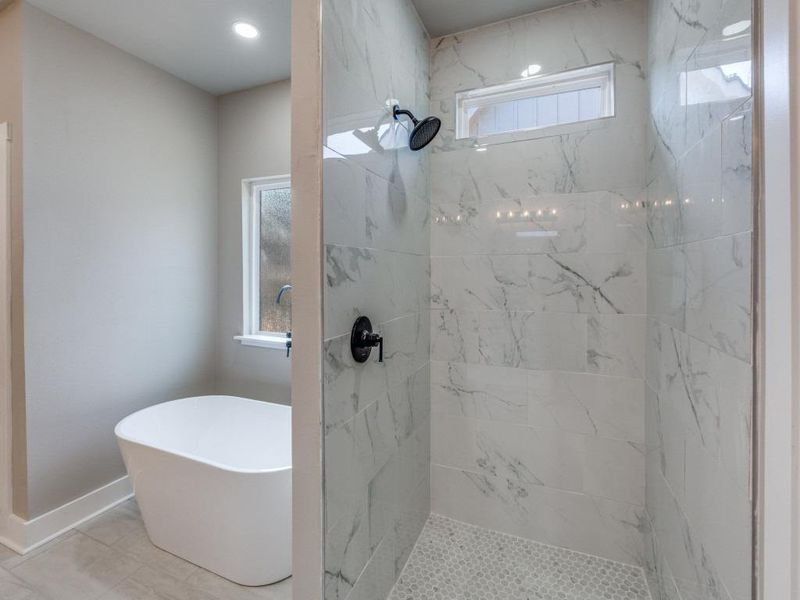 Full bath featuring a marble finish shower and a freestanding tub