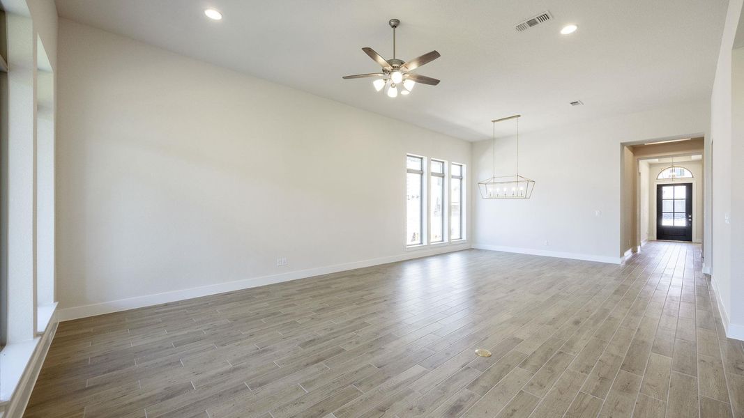 Empty room with ceiling fan, light wood-style flooring, a chandelier, baseboards, and recessed lighting Empty room with ceiling fan, light wood-style flooring, a chandelier, baseboards, and recessed lighting