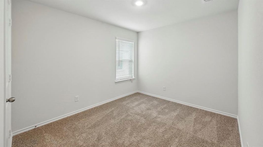 Neutral-toned wall paint and textured carpeting define this interior room, featuring a window with blinds